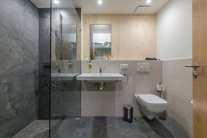 Un baño moderno con ducha de vidrio, lavamanos y retrete.