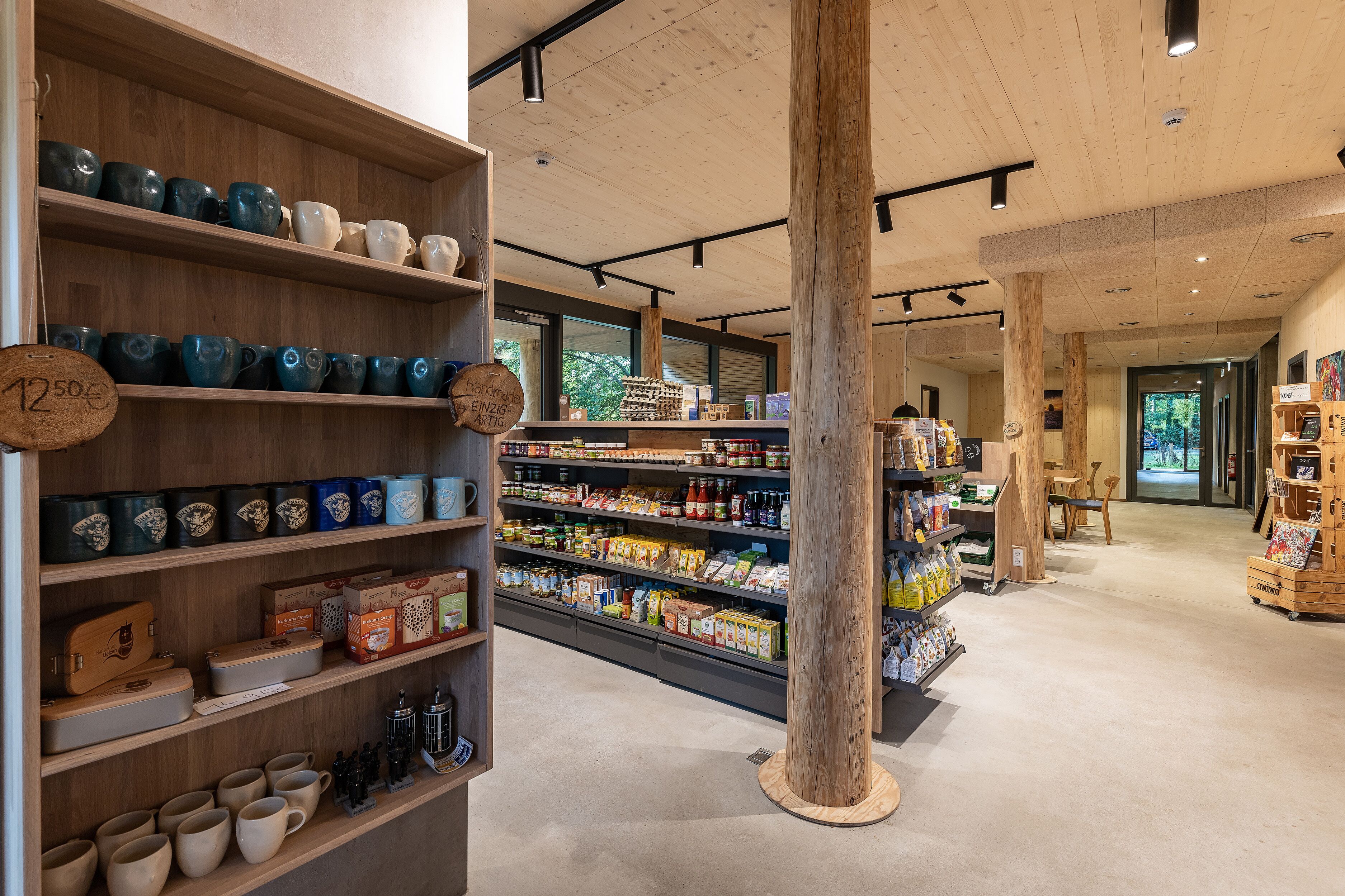 A store with shelves of ceramic mugs and boxes, wooden display stands, and a variety of packaged goods.