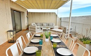 A dining area with a table set for six, outdoor seating, and a covered patio.