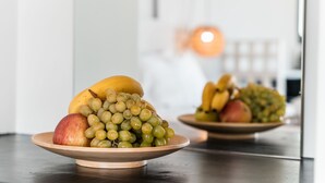 A wooden fruit bowl with grapes, an apple, and a banana on a dark countertop. - IfestAu.4 Suites Superior sea view (Santorini)