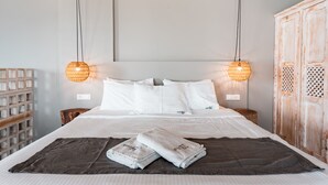A neatly made bed with white linens, two bedside lamps, and a wooden wardrobe. - IfestAu.4 Suites Superior sea view (Santorini)