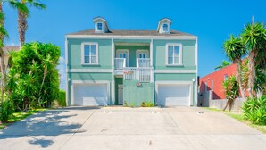 A two-story house with a front garage, a balcony, and a clear driveway. - Casa Caracol - Pool - Walk to the Beach, WiFi (South Padre Island)