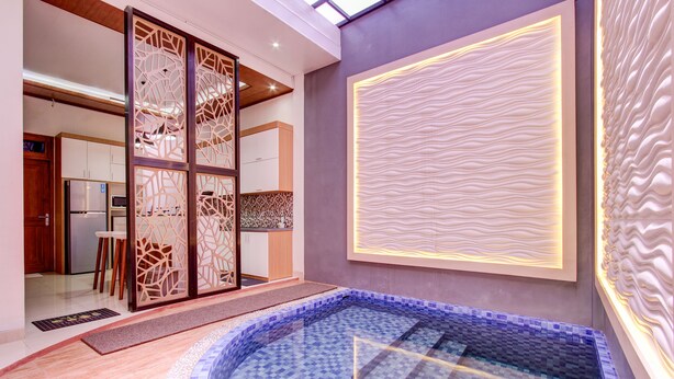 A modern interior with a central pool area, a kitchen in the background, and decorative wall panels. - Capital O 93718 Homestay 3 Bidadari (Moyudan)