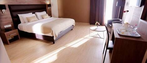 A modern hotel room with a large bed, bedside tables, a small desk, and a chair.