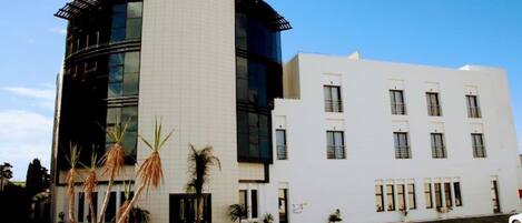 A LE ZENITH HOTEL with a modern design, featuring a curved facade and multiple windows.