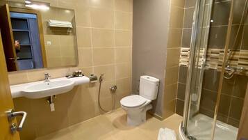 Un baño moderno con lavamanos, inodoro y cabina de ducha con mampara de vidrio.