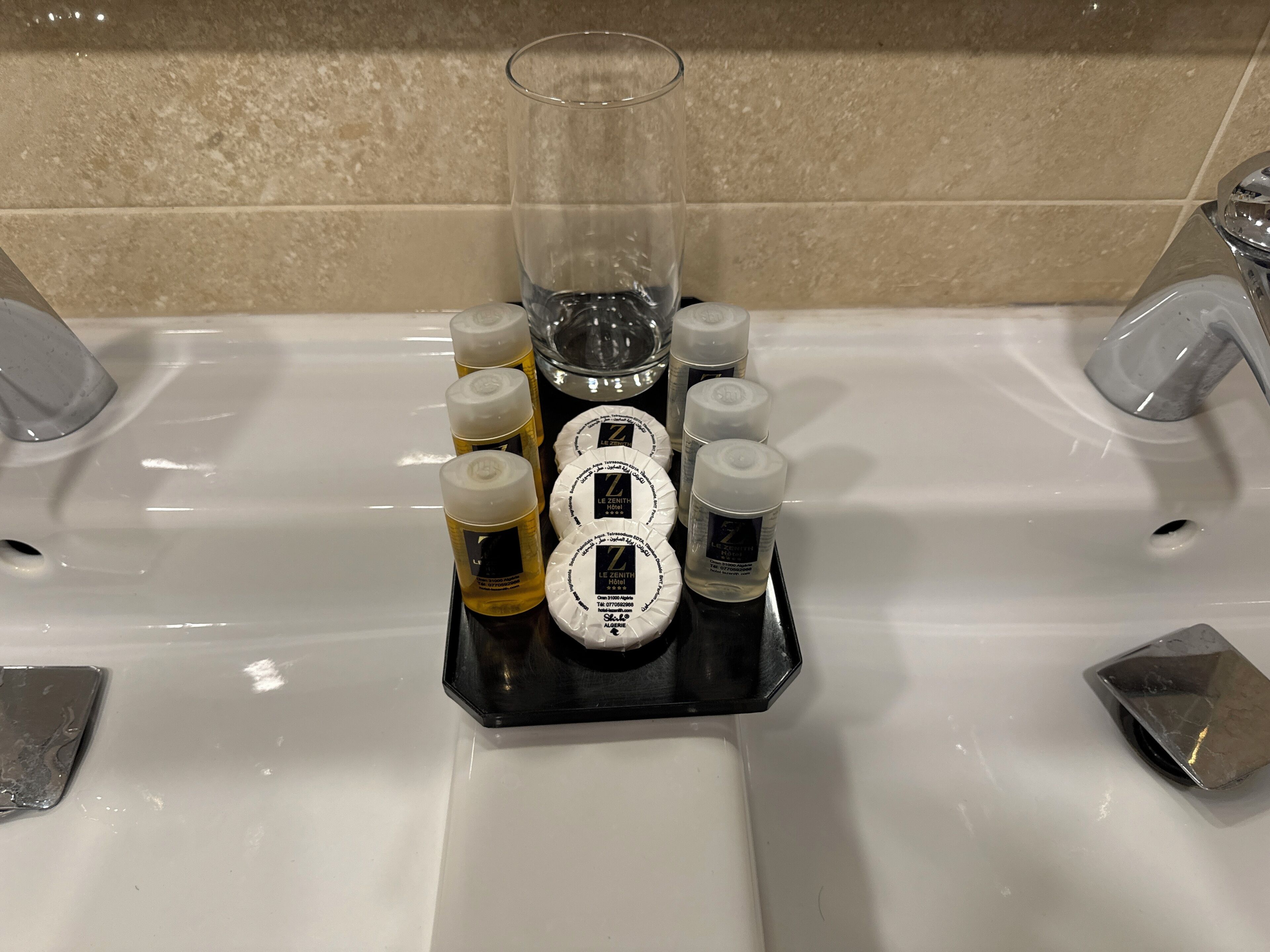 A bathroom sink with toiletries organized in a black tray.