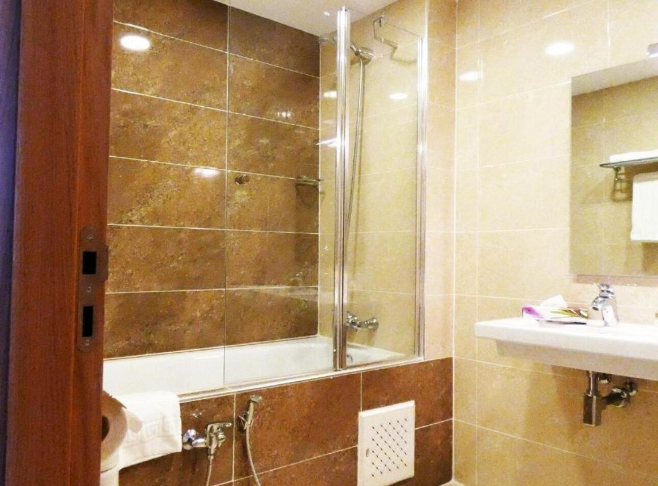 Une salle de bain avec une douche à parois de verre, un lavabo blanc et un miroir au-dessus du lavabo.