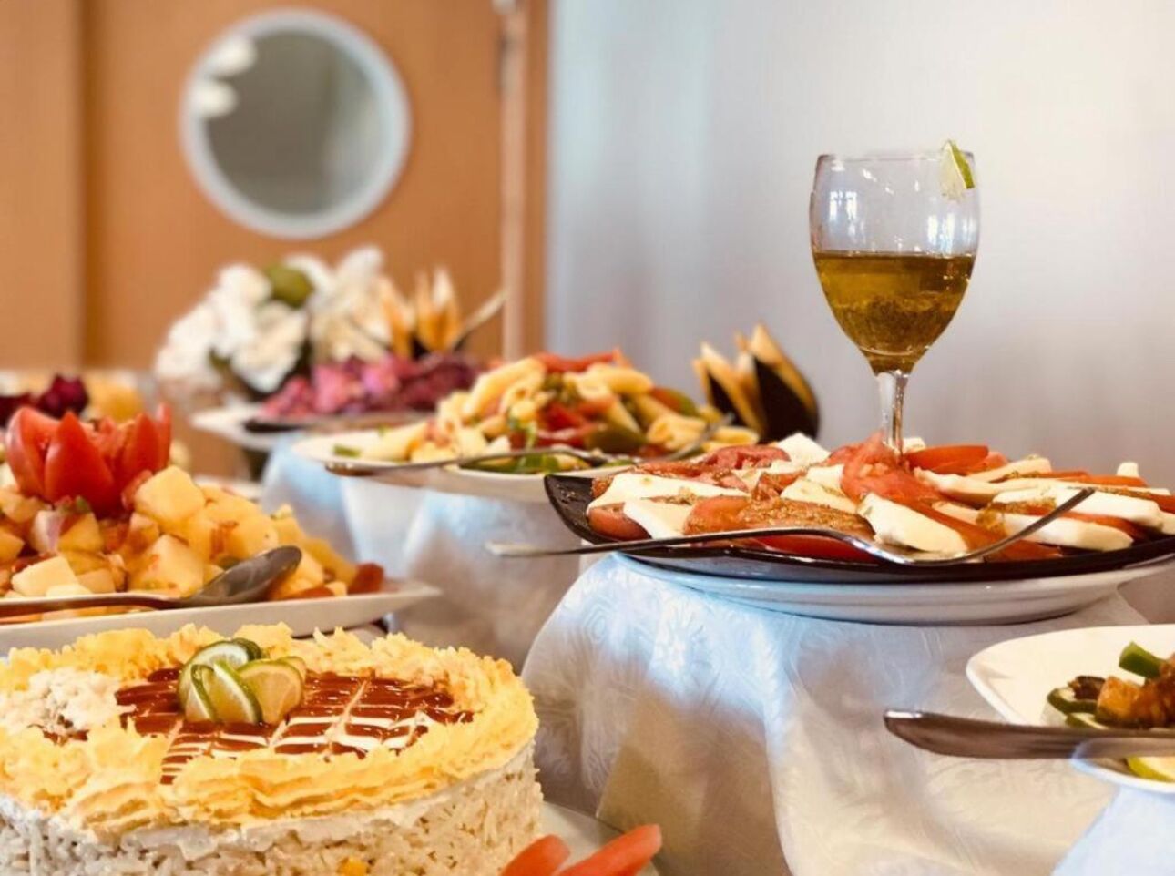 A buffet with various dishes and a glass of wine.