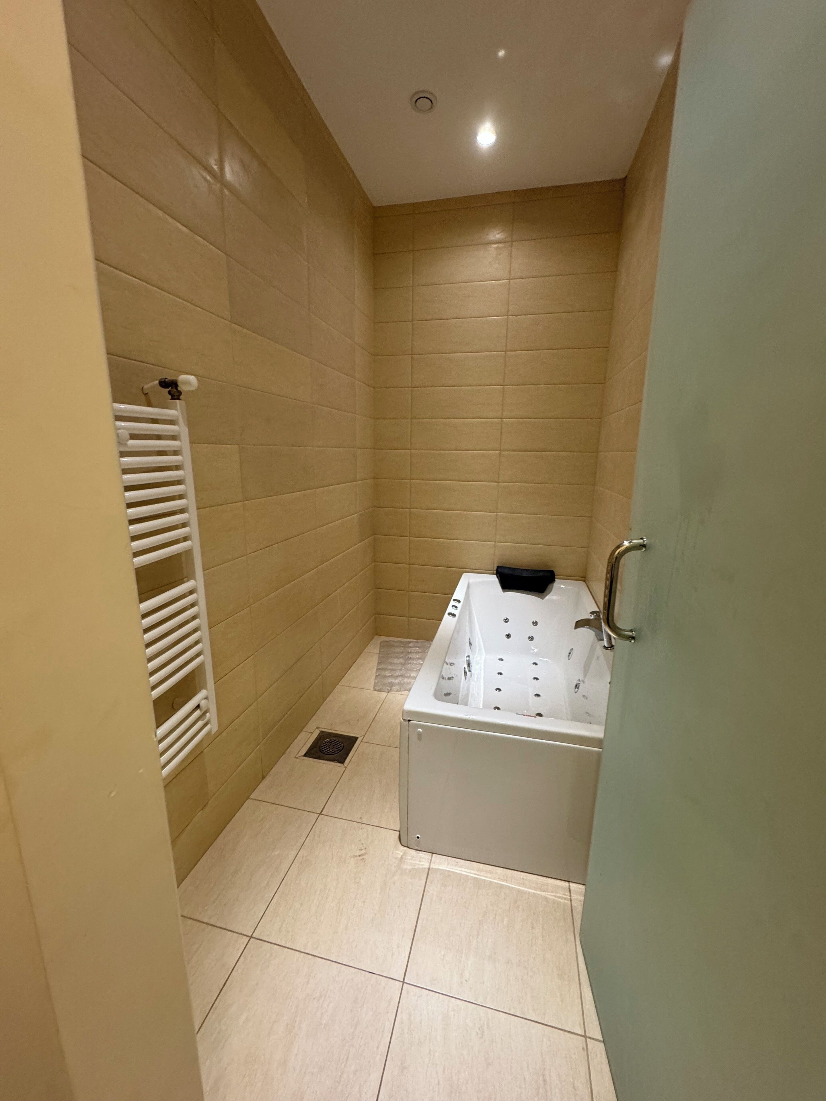 A bathroom with a bathtub, a towel rack, and tiled walls.