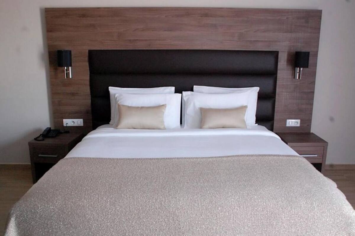 A hotel room with a large bed, two bedside tables, and a wooden headboard.