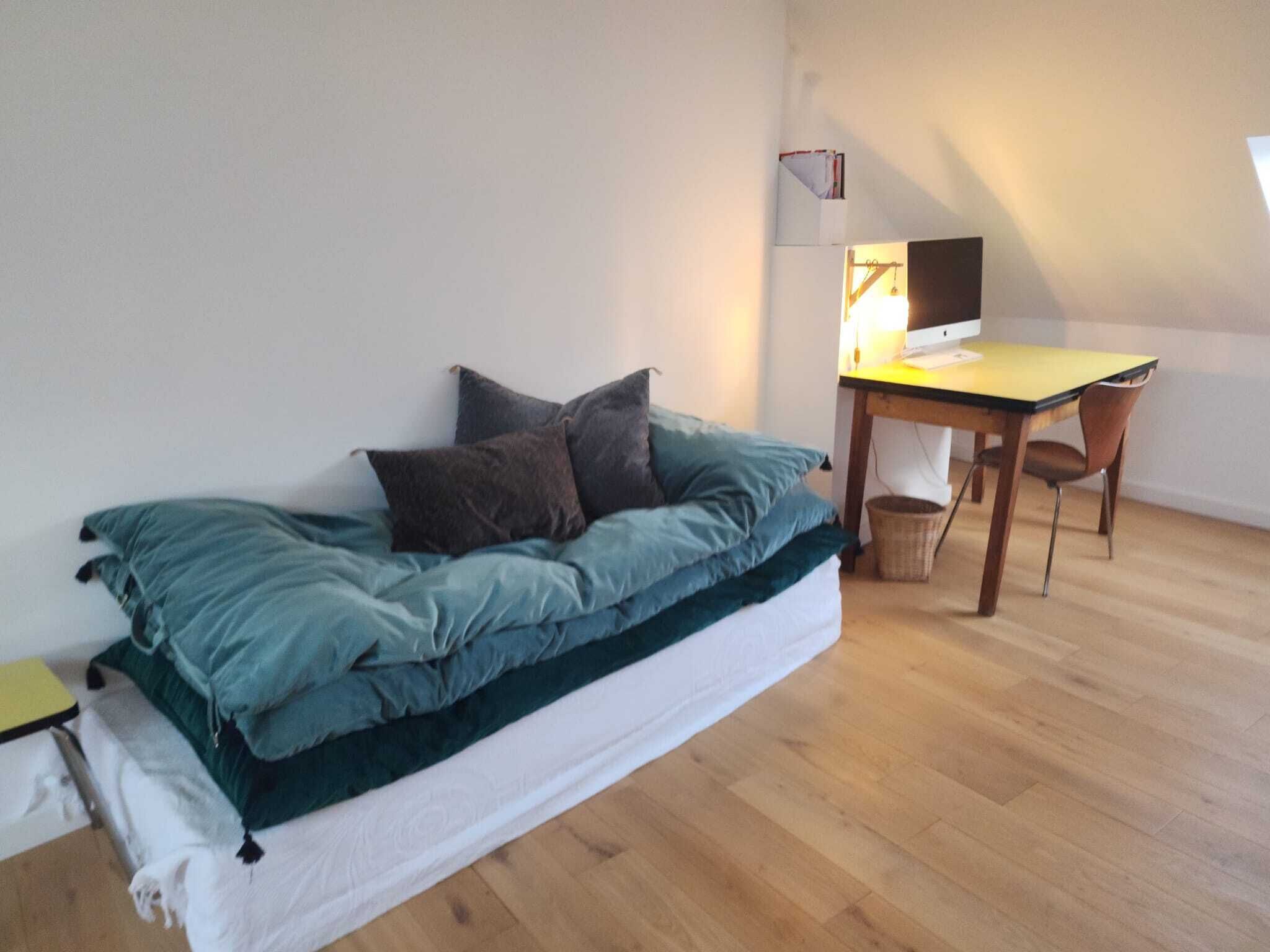 Una habitación estilo loft con una cama, un escritorio y una computadora.