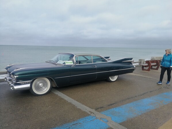 A vintage black car parked by the sea.