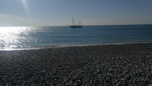 A pebbled beach with a boat in the water. - Fisherman's cottage / historic center (fecamp)