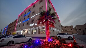Un edificio con un cartel que indica 'Serviced Apartments' y una cafetería.