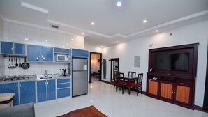 Una cocina moderna con armarios azules, un comedor con mesa de madera y un televisor sobre un mueble de madera.
