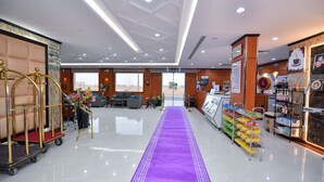 Un hall de hotel con alfombra morada, un mostrador de recepción y una estación de café.