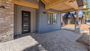 A modern building with a stone facade, a black door, and a covered patio area. - Large 5BR w hot tub, fireplace, forest views! (Flagstaff)