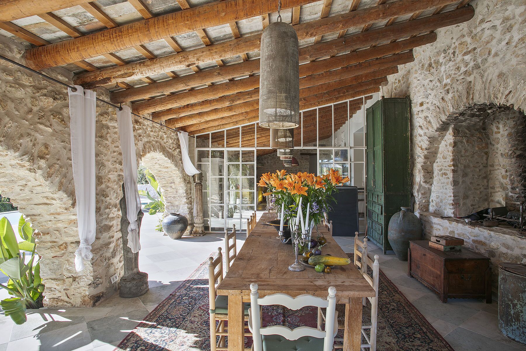 A rustic dining area with a wooden table, chairs, and a hanging light fixture.