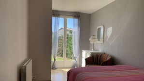 Een slaapkamer met een bed, een kaptafel, een spiegel en uitzicht op de omgeving door een glazen deur.