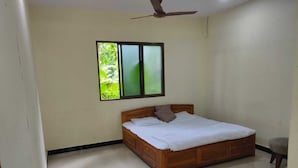 Un dormitorio con una cama de madera, un ventilador de techo y una ventana con vistas a zonas verdes.