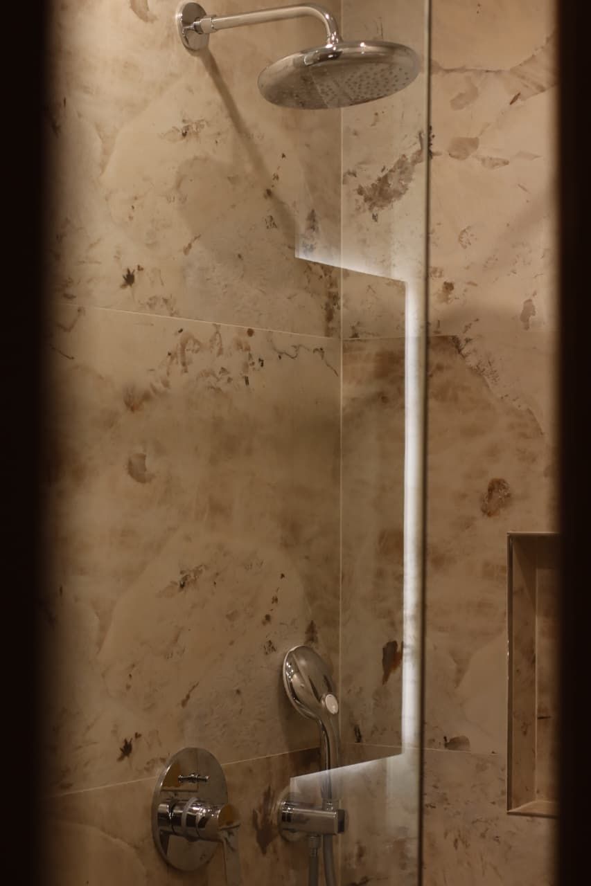 Une douche équipée d’un pommeau de douche à main et d’un robinet fixé au mur.