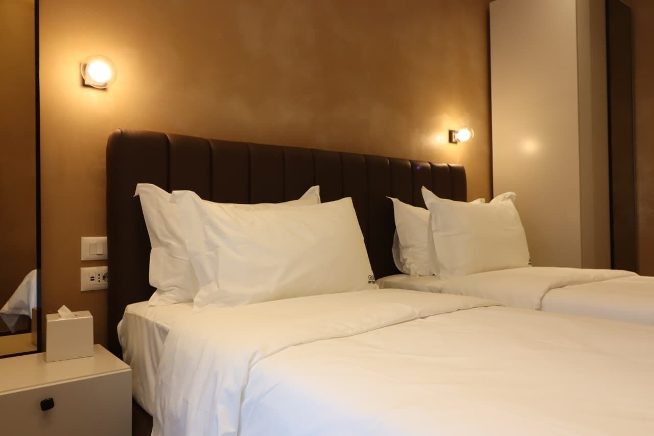 Een hotelkamer met twee bedden, een nachtkastje en een wandlamp.