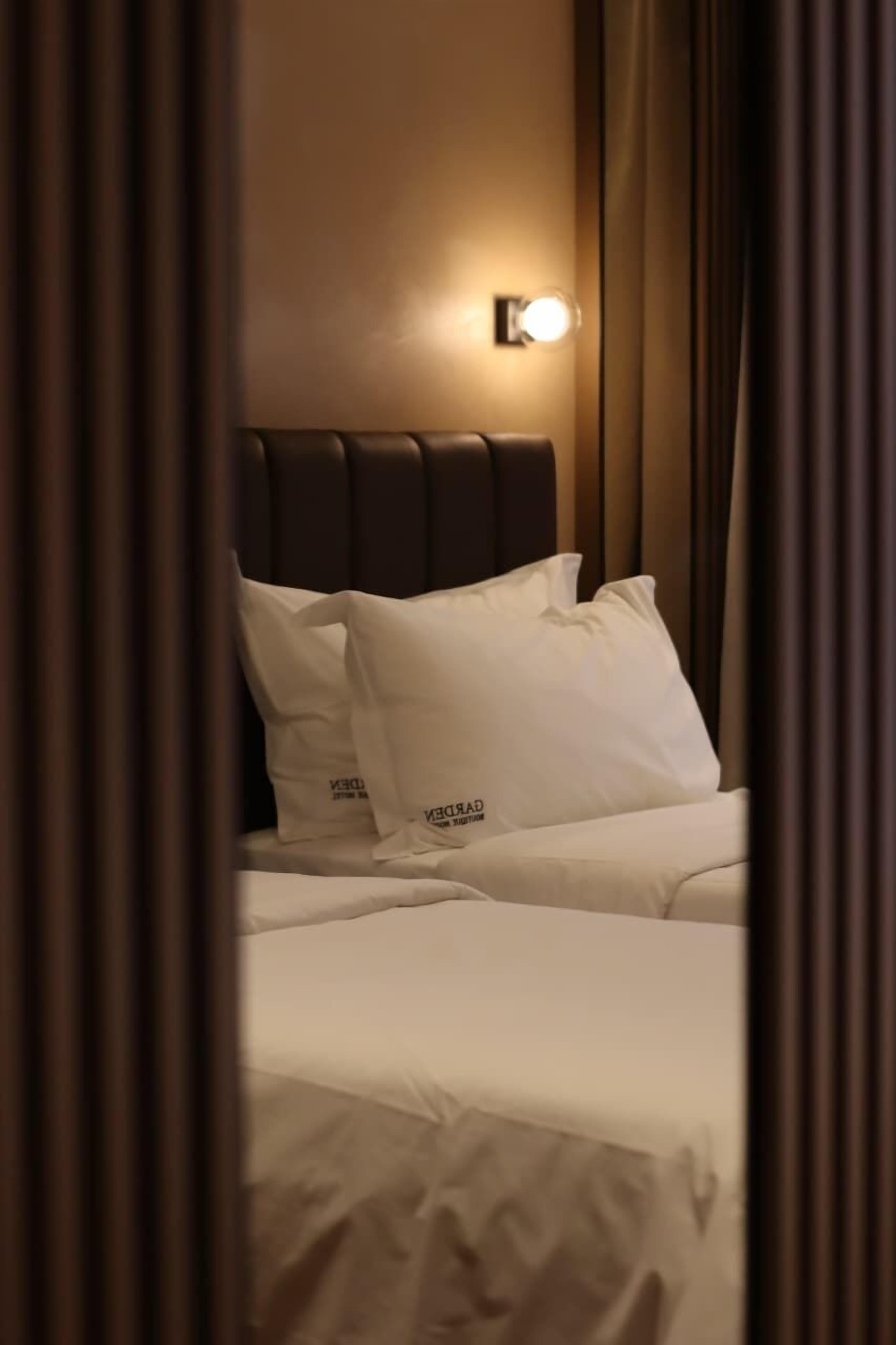 Ein Hotelzimmer mit Bett, weißer Bettwäsche und einem Kopfteil mit einer Leuchte.
