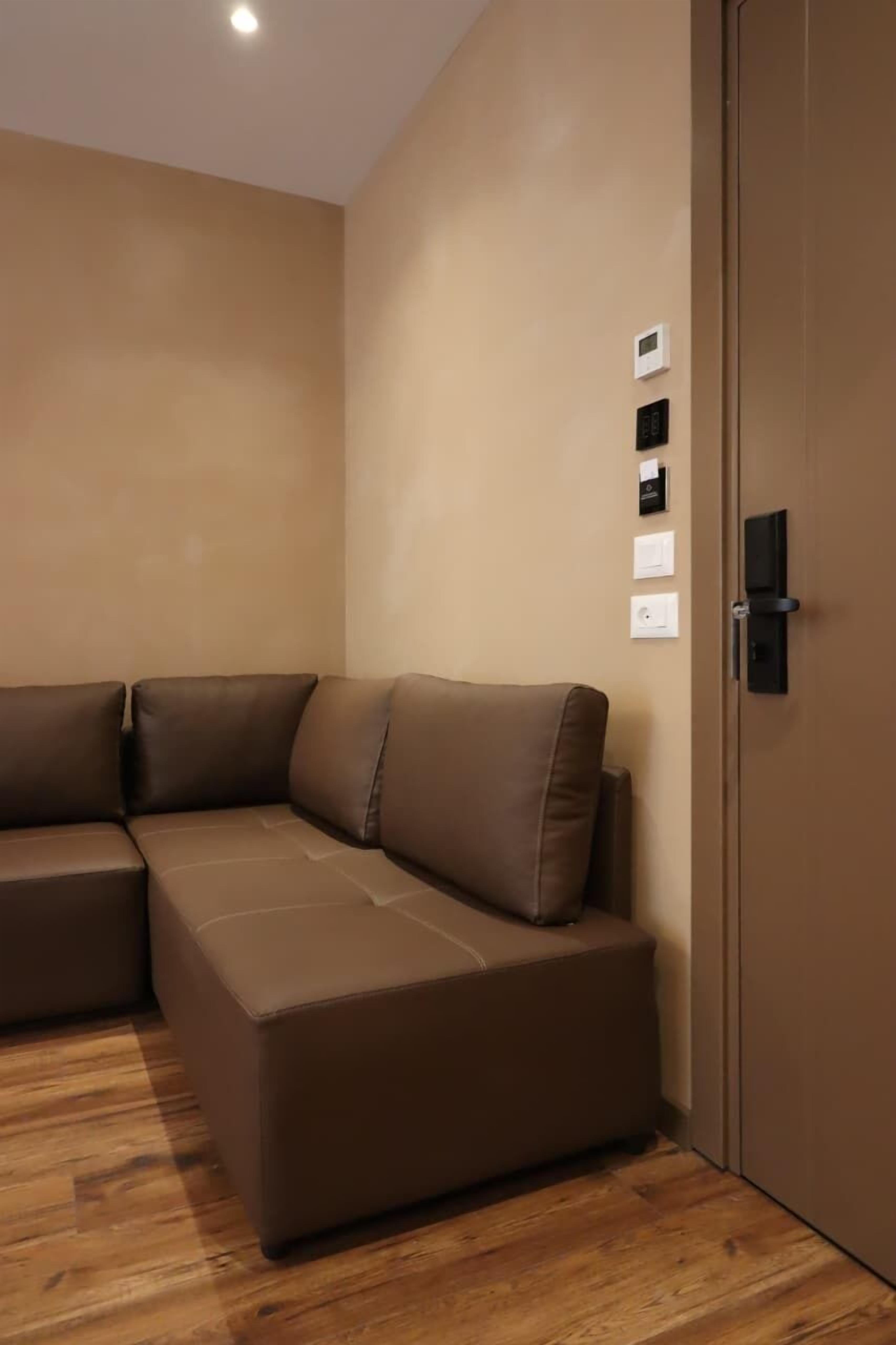 A modern room with a sectional sofa, a wooden floor, and a door with a handle.