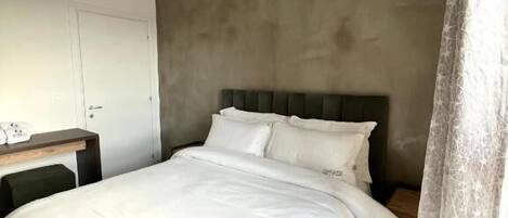 Een moderne slaapkamer met een groot bed, een nachtkastje, een kledingkast en een airconditioner aan de muur.