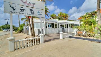 A Belmar Oceanfront Apartments sign with amenities like a pool, coffee, and a restaurant.