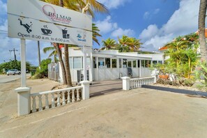 Une enseigne indiquant les appartements Belmar, situés en bord de mer, et mentionnant les commodités offertes, comme une piscine, un service de café et un restaurant.