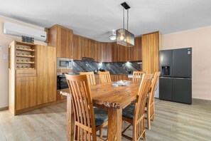 Une cuisine moderne avec des meubles en bois, un réfrigérateur noir, un four à micro-ondes et une table à manger avec des chaises.