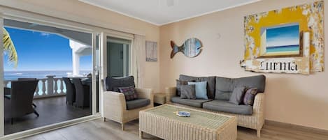 Ein Wohnzimmer mit Meerblick, einem Deckenventilator und einer Wand mit Fischdekor und einem gerahmten Bild.