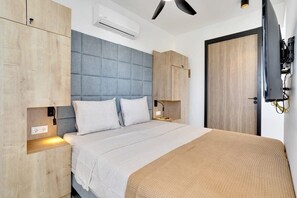 Un dormitorio moderno con una cama grande, armario empotrado, mesitas de noche y un ventilador de techo.