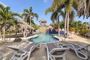 A pool area with lounge chairs, a stone structure, and palm trees.