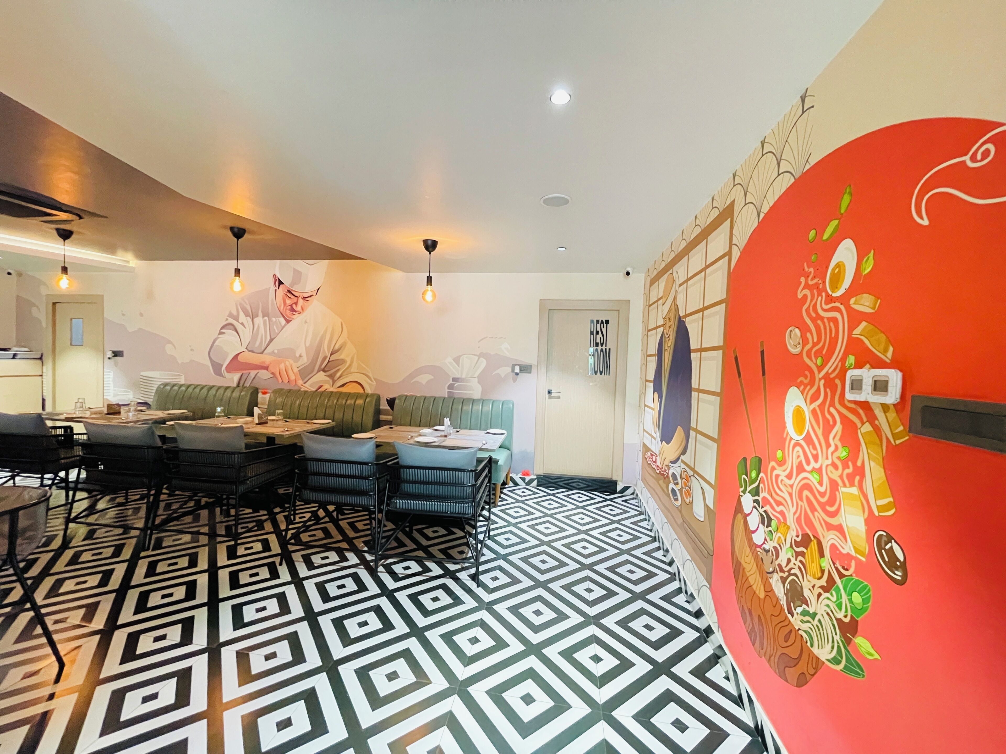 A dining area with a patterned floor, green cushioned seating, and a mural of a chef.