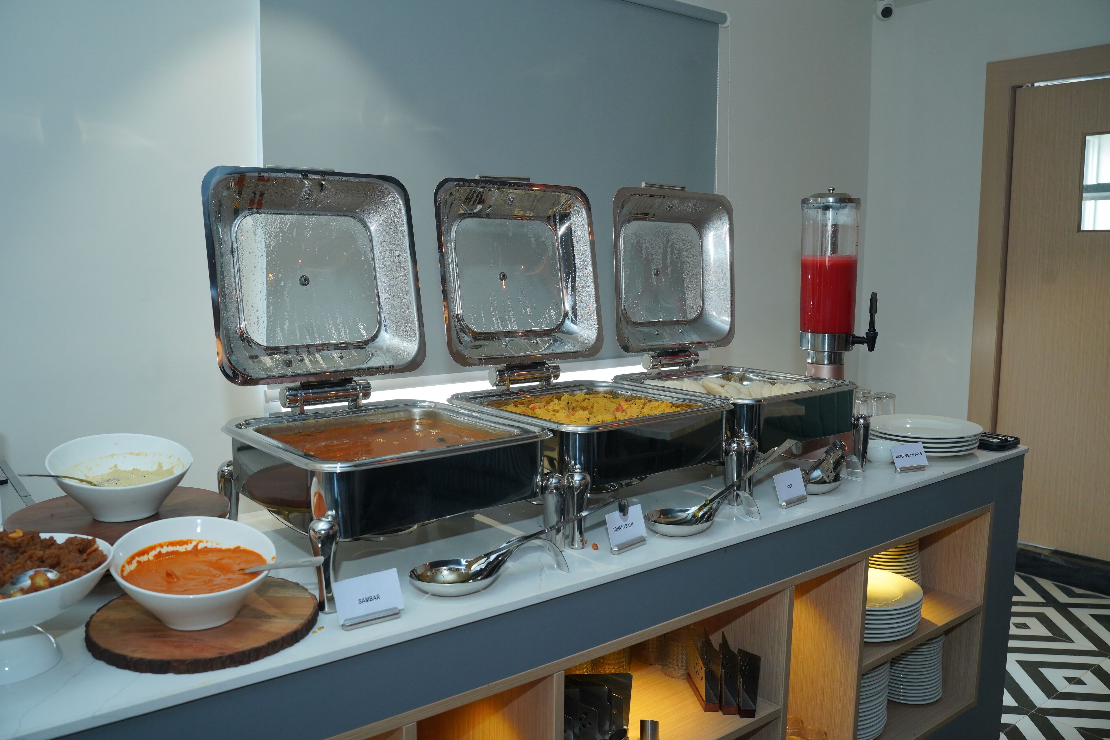 A buffet setup with various food items and a juice dispenser.