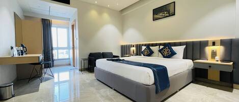 A modern hotel room with a large bed, a desk, a chair, a nightstand, and a ceiling fan.