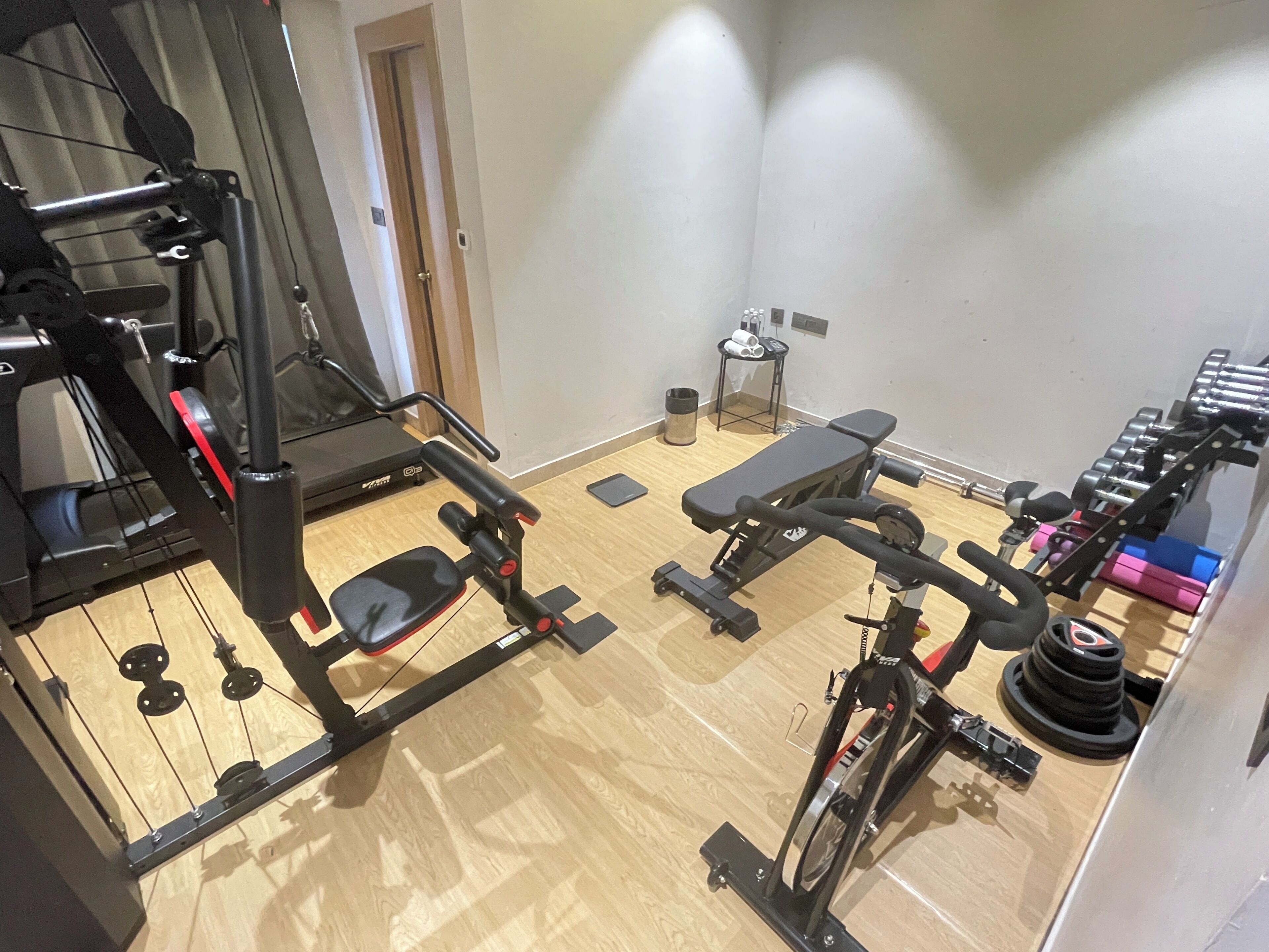 A gym with exercise equipment, a bench, and dumbbells.