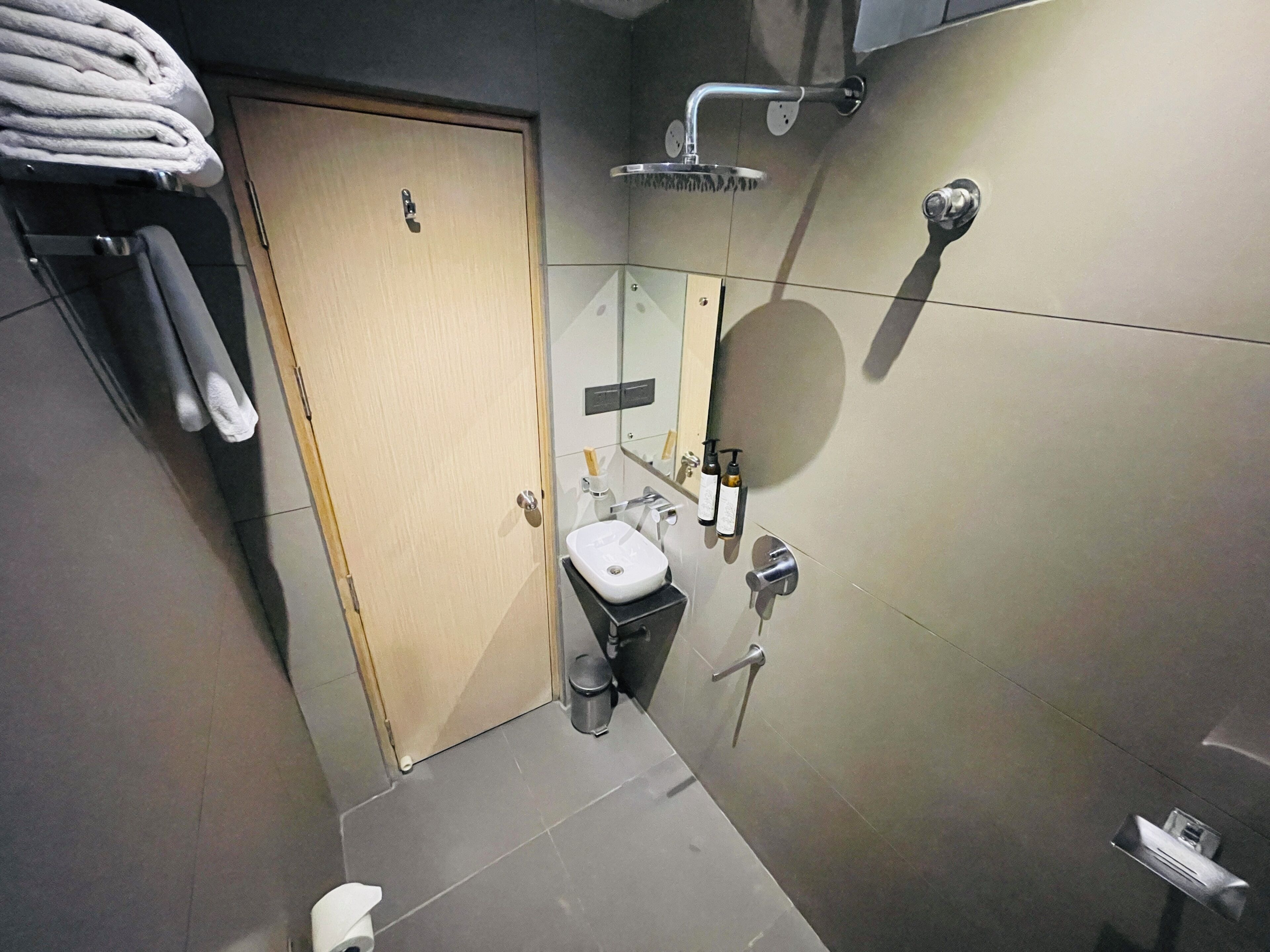 A bathroom with a toilet, sink, towel rack, and a shower.