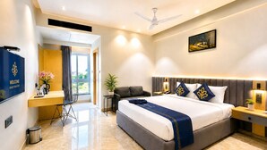 A modern hotel room with a large bed, a desk, a chair, a TV, and a ceiling fan. - Hotel Kyzen - Hitec city, Hyderabad (Hyderabad)