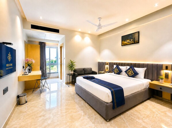 Una habitación de hotel moderna con una cama grande, un escritorio, una silla, un televisor y un ventilador de techo.