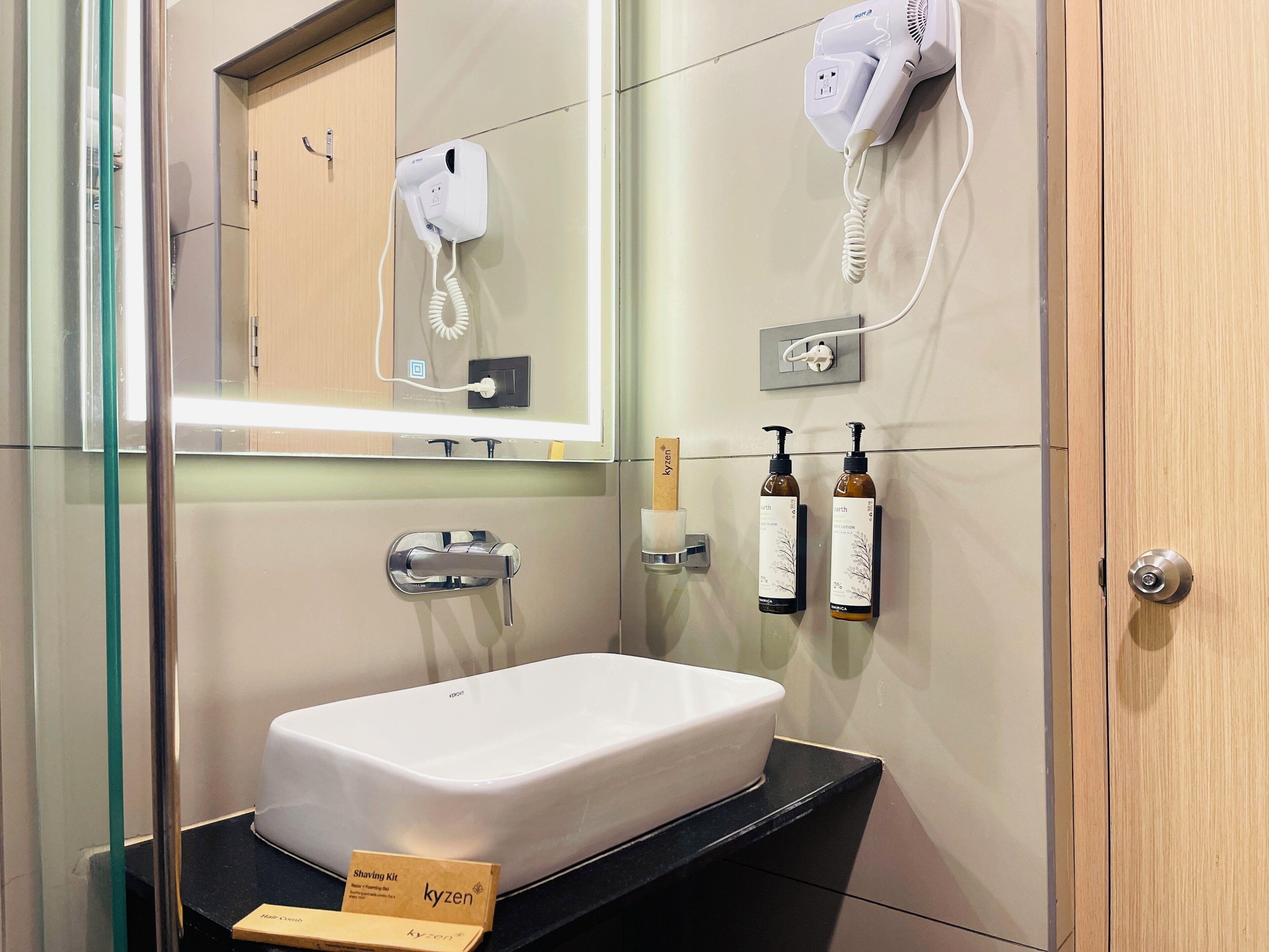 A bathroom with a white sink, a mirror, a hairdryer, and two bottles of lotion.