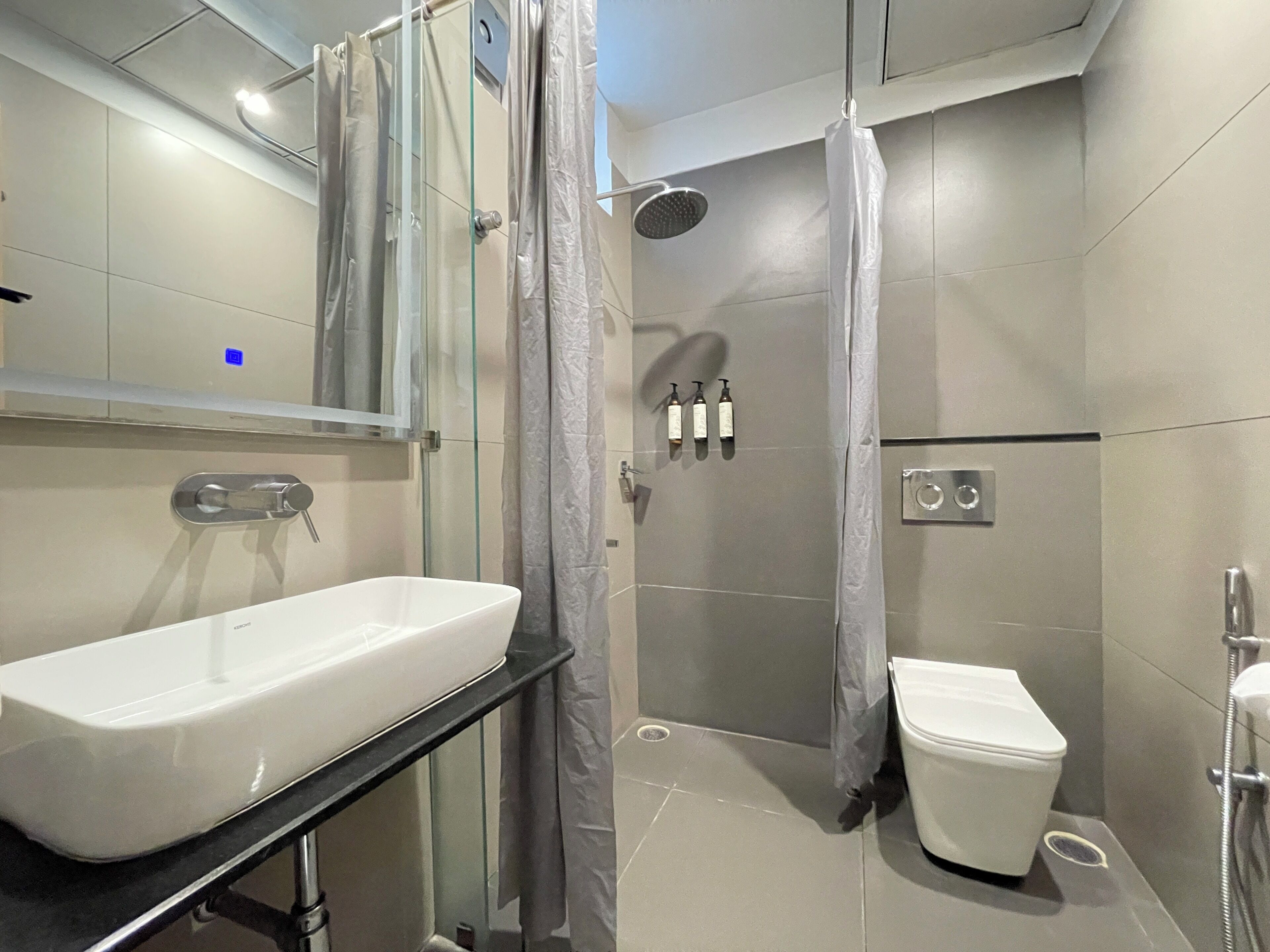 A modern bathroom with a glass shower enclosure, a white sink, and a toilet.