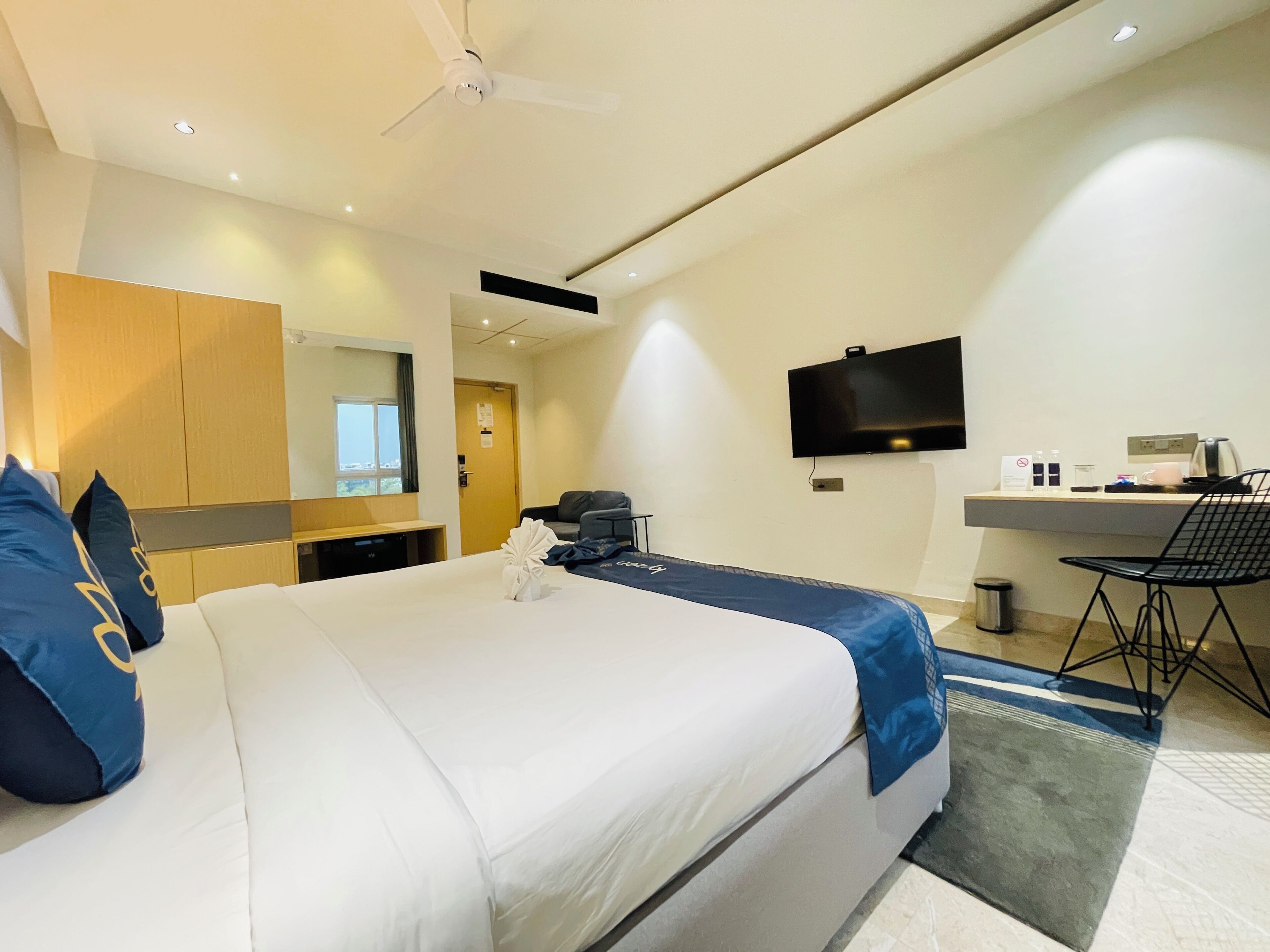 Ein Hotelzimmer mit Bett, Schreibtisch, Fernseher und Stuhl.