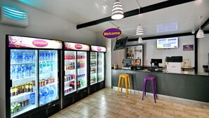 A clean, modern interior with multiple beverage dispensers, a bar area, and a 'Welcome' sign. - SleepOver Punda Maria  (Thulamela)