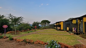 A modern building with a black and yellow exterior, a paved pathway, and a sign indicating a 24-30 hour service area. - SleepOver Punda Maria  (Thulamela)