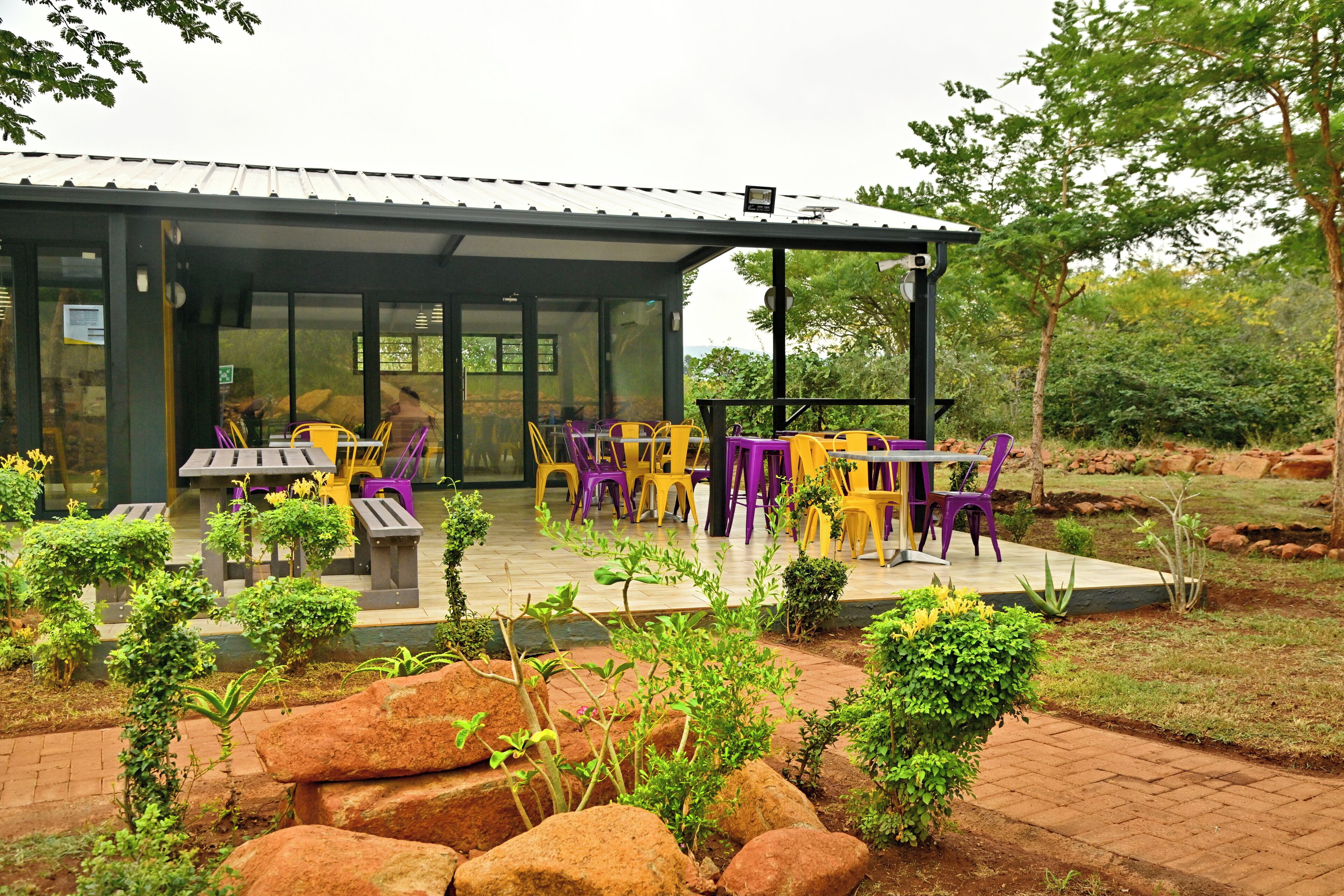 An outdoor seating area with tables and chairs, surrounded by rock formations and greenery.