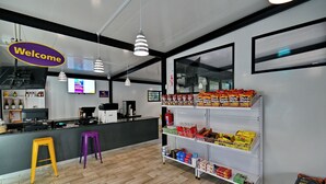 A clean, modern interior with a reception area, bar, and shelves stocked with snacks. - SleepOver Punda Maria  (Thulamela)